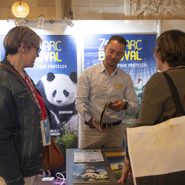 Métier du Zoo : Conseiller de Clientèle Groupes - Emploi - ZooParc de Beauval - Commercial de Beauval discutant avec des clients lors d’un salon