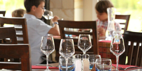 Métier des hôtels : Maître d'Hôtel - Domaine d'activité : Salle - Table dressée dans un restaurant avec enfants installés derrière